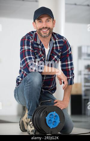 homme avec une bobine de câble d'extension électrique Banque D'Images