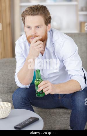 homme avec une bouteille de bière regardant la télévision Banque D'Images