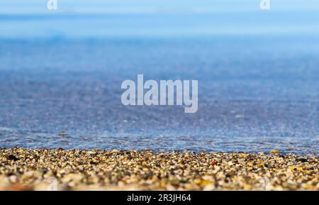 Un fond de sable, de petits cailloux et de vagues sur la plage de la mer. Concept de vacances d'été Banque D'Images