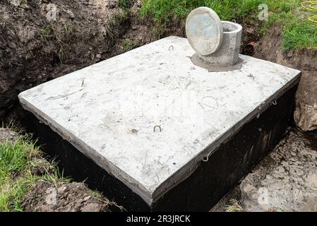 Fosse septique en béton d'une capacité de 10 mètres cubes placée dans le jardin près de la maison, eau visible en dessous. Banque D'Images