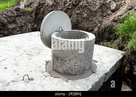 Fosse septique en béton d'une capacité de 10 mètres cubes placée dans le jardin près de la maison, eau visible en dessous. Banque D'Images