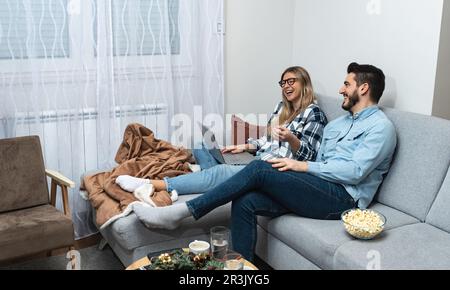 Jeune heureux beau couple planifiant le budget ensemble à la maison, écrivant des notes à l'ordinateur portable, la création de liste de contrôle pour les achats ou la liste d'invités pour weddin Banque D'Images