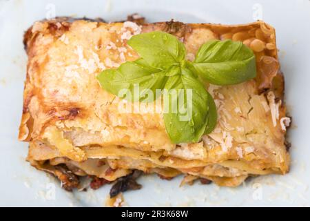 Lasagnes avec salade sur une assiette blanche Banque D'Images