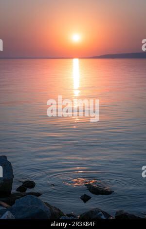 Le soleil surmonte l'horizon au coucher du soleil sur le lac Balaton Banque D'Images