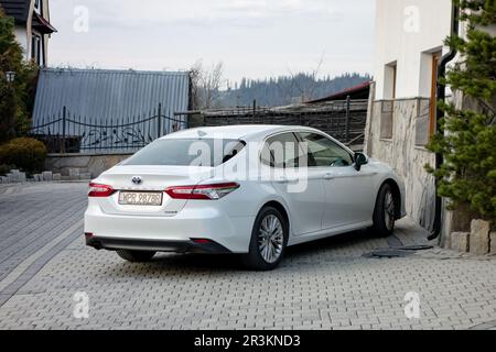 MURZASICHLE, POLOGNE - 28 AVRIL 2023 : berline blanche hybride Toyota Camry garée en face de l'hôtel à High Tatras en Pologne Banque D'Images