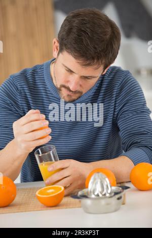 l'homme presse des oranges pour obtenir un jus d'orange Banque D'Images