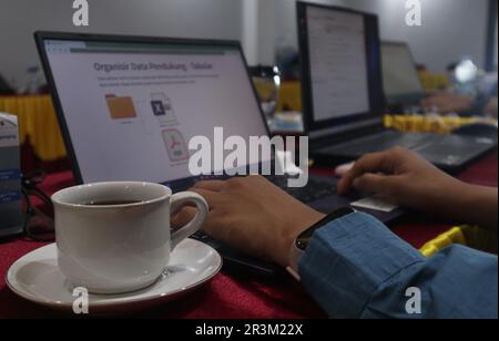 Vue rapprochée d'un bureau confortable avec ordinateur portable, d'une grande tasse de café et de fournitures de bureau. Banque D'Images