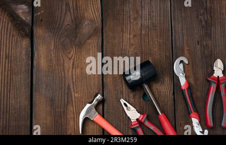 Ensemble d'outils de construction sur fond de bois marron, vue de dessus. Marteau, pince, clé réglable Banque D'Images