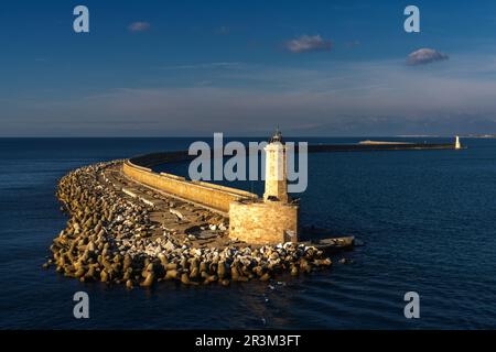 Mur du port en pierre et jetée avec phare dans la lumière chaude du matin dans le port de Livourne Banque D'Images