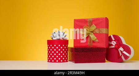 Une pile de boîtes-cadeaux enveloppées de papier coloré sur fond jaune. Joyeuses fêtes Banque D'Images