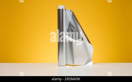 Rouleau de papier d'aluminium torsadé pour l'emballage des aliments sur fond jaune Banque D'Images