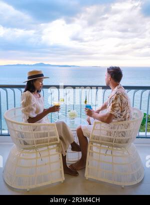 Deux hommes et femmes qui boivent des cocktails sur le balcon d'un hôtel à Pattaya en Thaïlande au coucher du soleil Banque D'Images