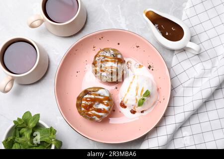 Délicieuses pommes cuites aux noix, à la crème glacée et au caramel servies sur une table blanche, à plat Banque D'Images