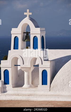 Terrasse d'une petite église orthodoxe avec ses trois Bells Tower dans le village d'Oia - Santorini Island, Grèce - Caldera View Banque D'Images