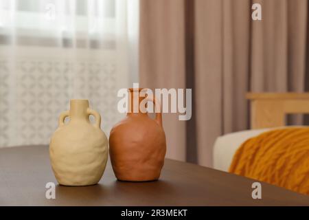 Différents vases sur table en bois et rideau de fenêtre pastel dans la chambre, espace pour le texte Banque D'Images