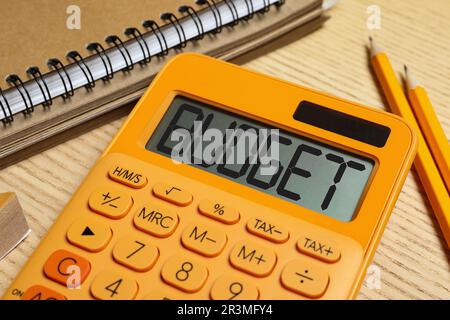 Calculatrice avec mot Budget, bloc-notes et crayons sur table en bois, gros plan Banque D'Images