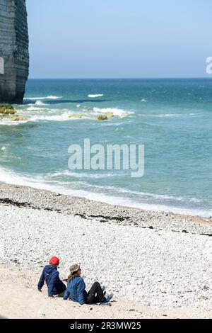 Couple amoureux le long de la mer assis ensemble en regardant l'horizon | couple d'amoureux assis sur une plage de galettes réglant l'horizon Banque D'Images