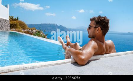 Santorini Greece Oia, jeunes hommes à la piscine avec vue sur l'océan de la caldeira Banque D'Images