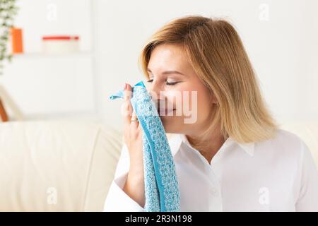 Belle femme sent des serviettes propres et souriant tout en faisant la lessive à la maison - concept d'adoucissant de tissu Banque D'Images