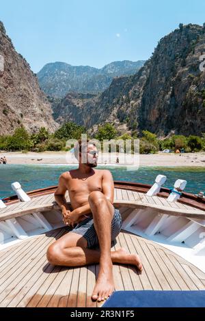 Un jeune homme se détendant sur un bateau en bois lors d'une excursion en bateau à la plage Butterfly à Fethiye Turquie Banque D'Images