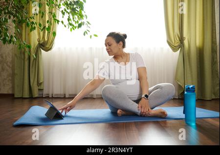 Femme enceinte consciente magnifique montres en ligne grossesse cours de yoga, pratique la relaxation et les exercices de souffle à la maison Banque D'Images