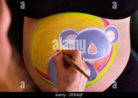 peinture à la main du ventre enceinte. Douche bébé et peinture de chambre Banque D'Images