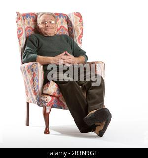 Les personnes âgées : un repos bien-être. Un homme âgé qui profite d'un moment de pause assis dans un fauteuil. Portrait sur toute la longueur, isolé sur blanc. D'une série. Banque D'Images