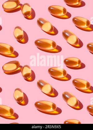 Vue de dessus composition de pilules de vitamine orange éparpillées sur fond rose dans le studio léger Banque D'Images