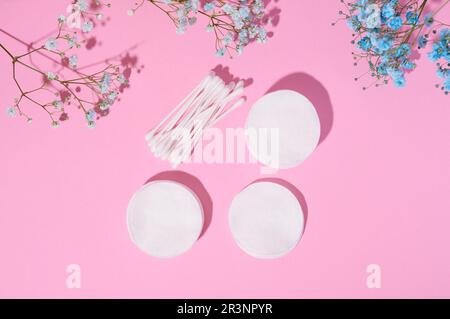 Tampons de cosmétiques en coton ronds et bourgeons en coton sur fond rose Banque D'Images
