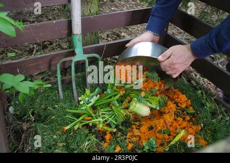 Compost de déchets organiques. Recyclage des aliments dans le jardin de la maison et vie durable. L'homme jette les restes de légumes et de fruits de cuisine pour la biodégradati Banque D'Images