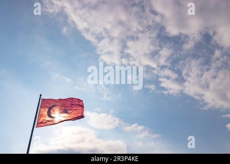 Une photo du drapeau turc contre un ciel bleu nuageux. Banque D'Images