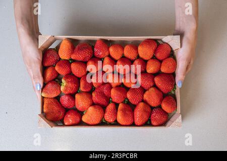 Femme tenant une boîte en bois avec des fraises Banque D'Images