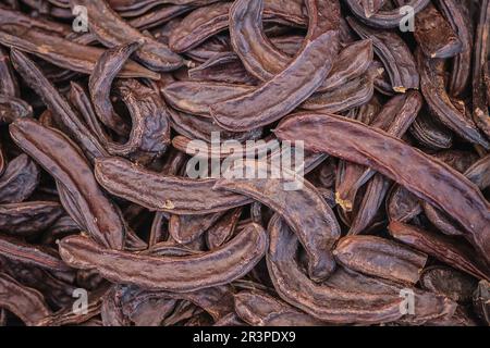 Caroube sur une table en bois, vue rapprochée. Des dosettes Sweet Carob biologiques sains Banque D'Images