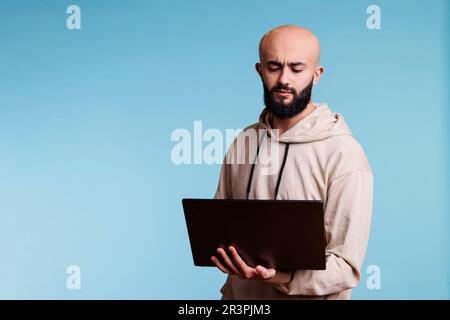 Homme arabe tenant un ordinateur portable, analysant le code Banque D'Images