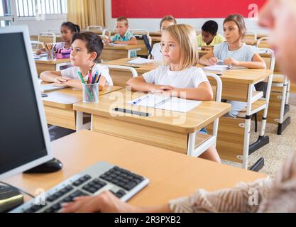 Diligent tweens étudiant en classe avec une enseignante Banque D'Images
