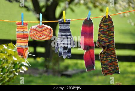 Chaussettes tricotées, gants et balle de laine sur une corde à linge dans le jardin, Allemagne Banque D'Images