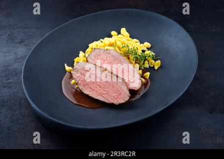 Tranches de veau torréfié Tafelspitz avec spaetzle souabe servies avec une sauce à la bière foncée dans une assiette design Banque D'Images