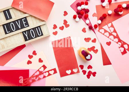 Contexte de la Saint-Valentin. Coeurs en papier, papier de couleur, coupe-papier et letterboard avec texte Banque D'Images