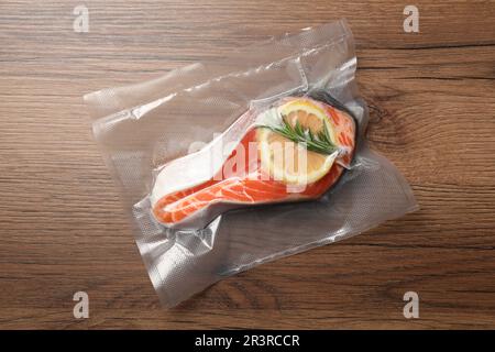 Saumon au citron dans un sac sous vide sur une table en bois, vue de dessus Banque D'Images