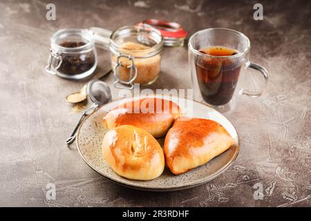Tartes douces à la pâte levée avec différentes garnitures sur plateau et verre de thé Banque D'Images