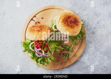 Deux hamburgers avec escalope de veau et herbes sur planche à découper en bois Banque D'Images