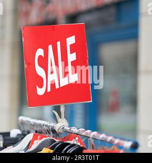 Affiche avec l'inscription Vente de vêtements à prix réduit sur offre spéciale devant un magasin Banque D'Images