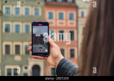 Une femme voyageur dans des lieux historiques regarde autour de la cour d'un monument et tourne de courtes vidéos par téléphone à Varsovie en Pologne. Photos touristiques lieu historique le jour ensoleillé. Femme méconnaissable Tourisme et blogging partage en ligne pour le public Voyage ensemble enregistrement vidéo sur téléphone mobile Banque D'Images