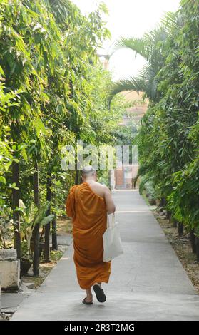 Un moine bouddhiste marchant dans le complexe Wat Chana Songkram en face de la route Khaosan à Bang Lamphu, Bangkok, Thaïlande. Banque D'Images