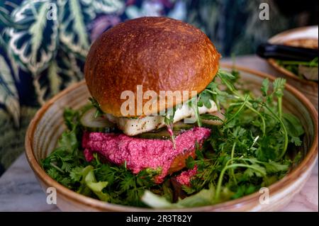 Hamburger lacto-végétarien, pain brioche rempli de fromage halloumi, cornichons, concombres et sauce au fromage de chèvre et de betterave. Banque D'Images