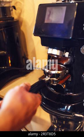 Le barista tient la main pour moudre les grains de café fraîchement torréfiés Banque D'Images