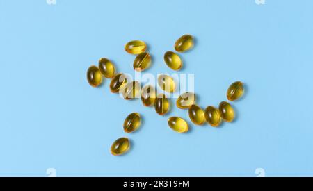 Capsules jaunes avec huile de poisson sur fond bleu, vue de dessus Banque D'Images