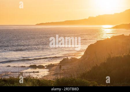 Les gens marchent le long de la plage au coucher du soleil à Playa de los lances sur le détroit de Gibraltar, Tarifa, Espagne Banque D'Images