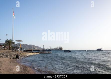 Coucher de soleil sur la plage d'Aqaba, fenêtre de la Jordanie sur la mer Rouge. En arrière-plan, l'impressionnant Flagpole et les installations portuaires Banque D'Images