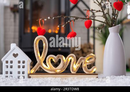 Clé à la maison avec porte-clés contre le fond de la cheminée poêle avec feu et bois de chauffage dans le décor de la Saint-Valentin, l'amour maison. Déplacement vers Banque D'Images